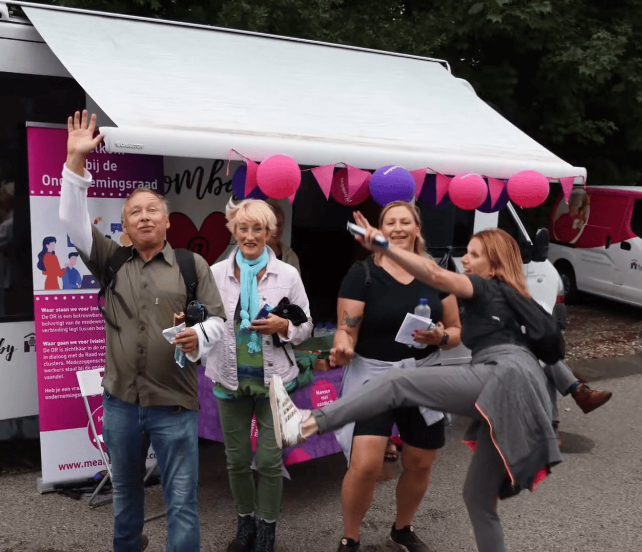 A lively party scene unfolds on a street, featuring a white truck with pink and purple balloons, streamers, and a group of people enjoying themselves.